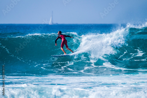 teenager surfing at the wave in tenerife playa de las americas - red wetsuits and beautiful and perfect wave