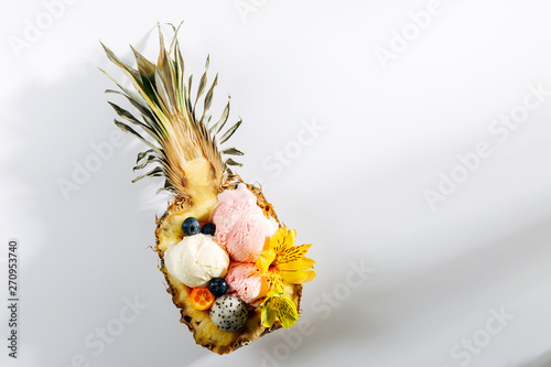 Balls of ice cream decoration flowers and berries in halves of  pineapple. Summer tropical concept. photo