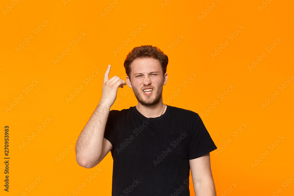 Studio shot of a bearded young man pointing a finger at the temple. Concept of a positive thinking. Studio shot of a bearded young man pointing a finger at the temple. Concept of a positive thinking.
