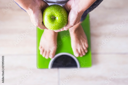 woman or man on a weight scale showing an apple and select his lifestyle - good nutition concept photo