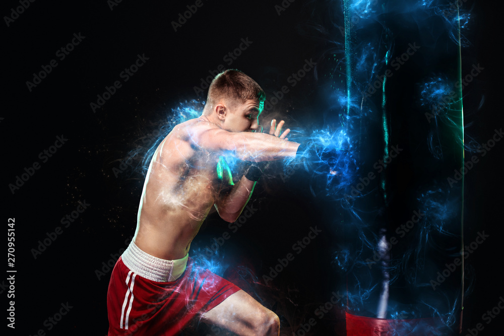 Sportsman, man boxer fighting in gloves with boxing punching bag. Isolated on black background with smoke. Copy Space.