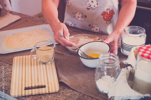 senior alone at home cooking fish at the kitchen -  very focused indoor - mature and caucasian 60s woman - retired woman