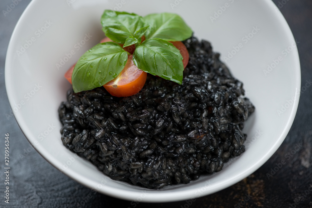Close-up of a white bowl with squid-ink risotto, selective focus, studio shot Close-up of a white bowl with squid-ink risotto, selective focus, studio shot