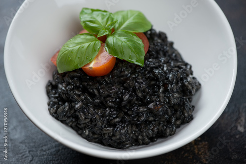 Close-up of a white bowl with squid-ink risotto, selective focus, studio shot
