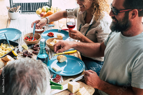 beautiful moment of family lifestyle at home eating and drinkng food or drinks at home on the table - man with sunglasses tking a vegetables - table full of food and salad outdoor photo