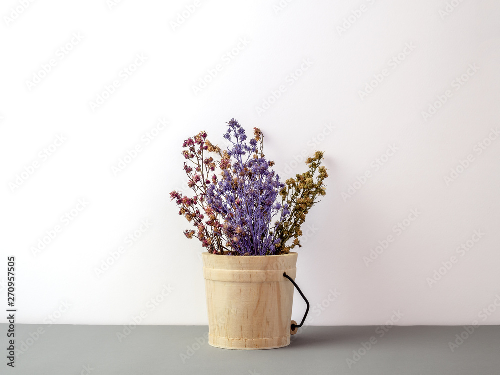Group of bouquet dried and wilted multiple color Gypsophila flowers in wood bucket on gray floor and white background