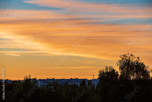 dramatic red sunset colors in the sky above trees and fields