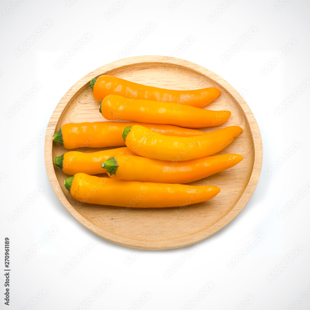 Yellow hot chili pepper in a wooden cup isolated on the white background. Yellow hot chili pepper in a wooden cup isolated on the white background.