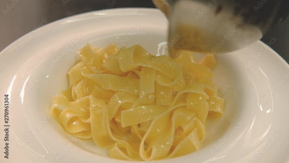 Shrimp Alfredo pasta recipe. Chef pouring cream sauce on cooked fettuccine Shrimp Alfredo pasta recipe. Chef pouring cream sauce on cooked fettuccine