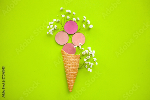 The concept of beauty and fashion. round pink blush with gypsophila in a cone for ice cream on a green background