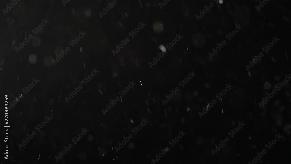Floating transparent motes are shining on a black studio background.