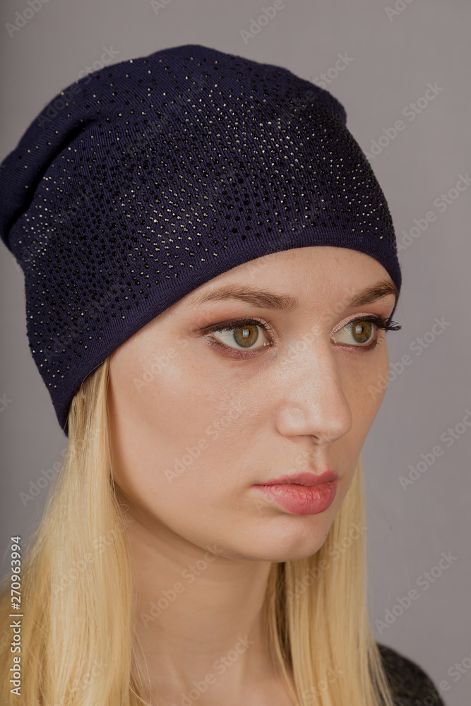 Portrait of a beautiful young girl in a stylish headdress with natural makeup on a gray background. Portrait of a beautiful young girl in a stylish headdress with natural makeup on a gray background.