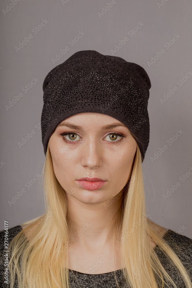 Portrait of a beautiful young girl in a stylish headdress with natural makeup on a gray background. Portrait of a beautiful young girl in a stylish headdress with natural makeup on a gray background.