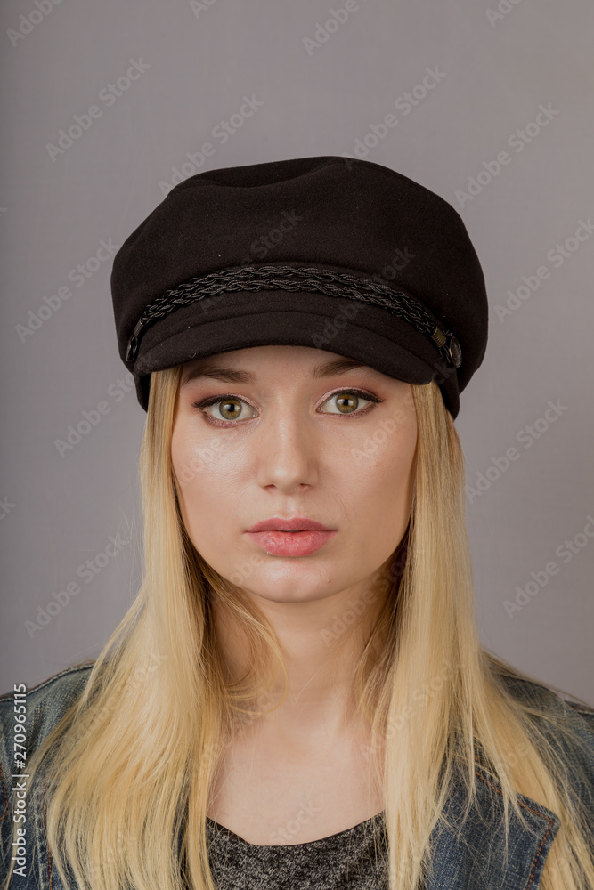 Portrait of a beautiful young girl in a stylish headdress with natural makeup on a gray background. Portrait of a beautiful young girl in a stylish headdress with natural makeup on a gray background.