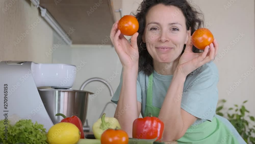 Eyes tomato. Cheerful woman in the kitchen having fun with vegetables. Eyes tomato. Cheerful woman in the kitchen having fun with vegetables.