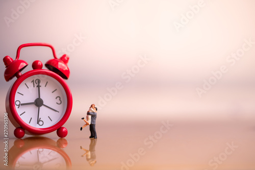 Miniature people: Small couple figures in love and red alarm clock. Love and Valentine's day concepts. family finance concept. Saving money for get marriage.