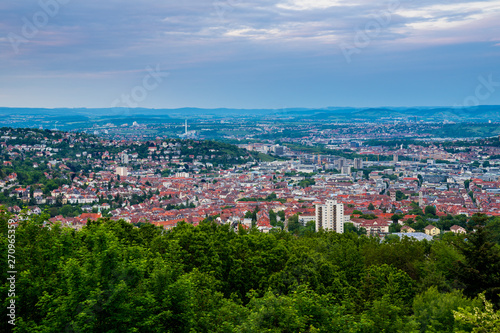 Germany, Houses of city stuttgart in valley surrounded by many hills and mountains forested with green trees in beautiful nature landscape