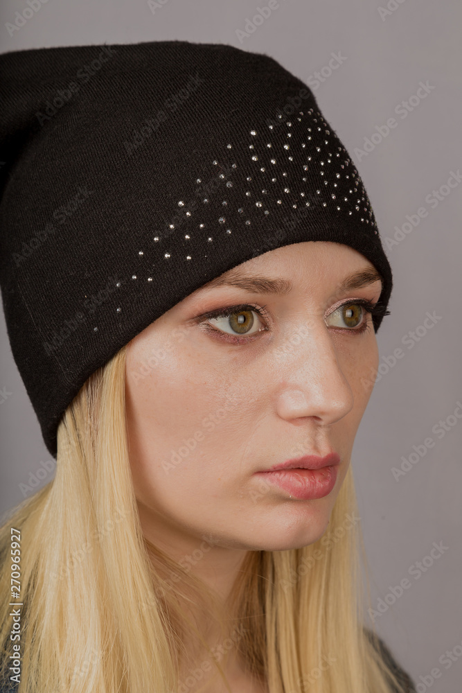 Portrait of a beautiful young girl in a stylish headdress with natural makeup on a gray background. Portrait of a beautiful young girl in a stylish headdress with natural makeup on a gray background.