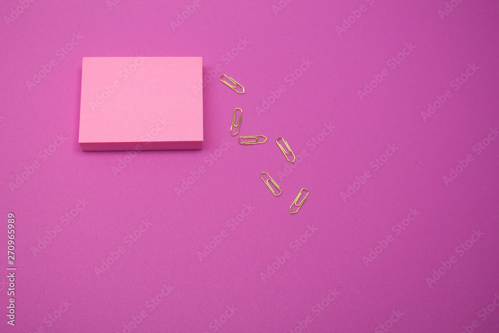 Pink reminder paper on pink background with gold paper clips Pink reminder paper on pink background with gold paper clips