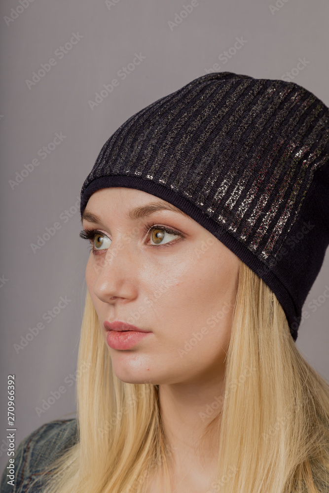 Portrait of a beautiful young girl in a stylish headdress with natural makeup on a gray background. Portrait of a beautiful young girl in a stylish headdress with natural makeup on a gray background.