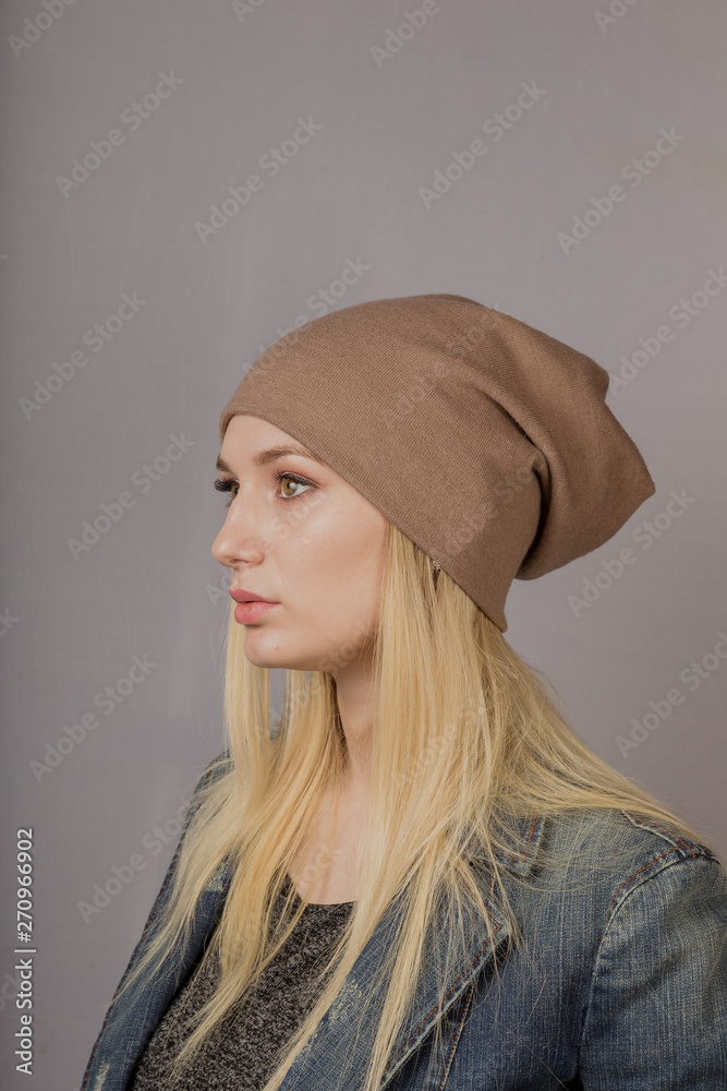 Portrait of a beautiful young girl in a stylish headdress with natural makeup on a gray background. Portrait of a beautiful young girl in a stylish headdress with natural makeup on a gray background.