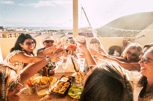 Womens having fun celebrating together outdoor - people group toasting with red wine and laughs - fun celebration concept with just female at home - active ladies laughing a lot photo