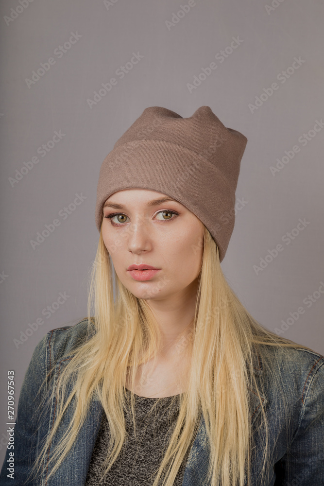 Portrait of a beautiful young girl in a stylish headdress with natural makeup on a gray background. Portrait of a beautiful young girl in a stylish headdress with natural makeup on a gray background.