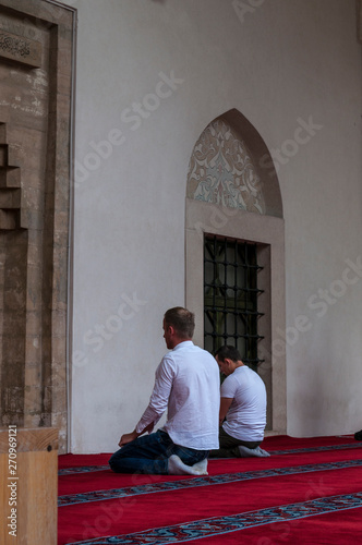 Sarajevo: muslim men praying in the direction of Mecca outside the Gazi Husrev-beg Mosque (1532), the largest historical mosque in Bosnia and Herzegovina in the Bascarsija neighborhood 