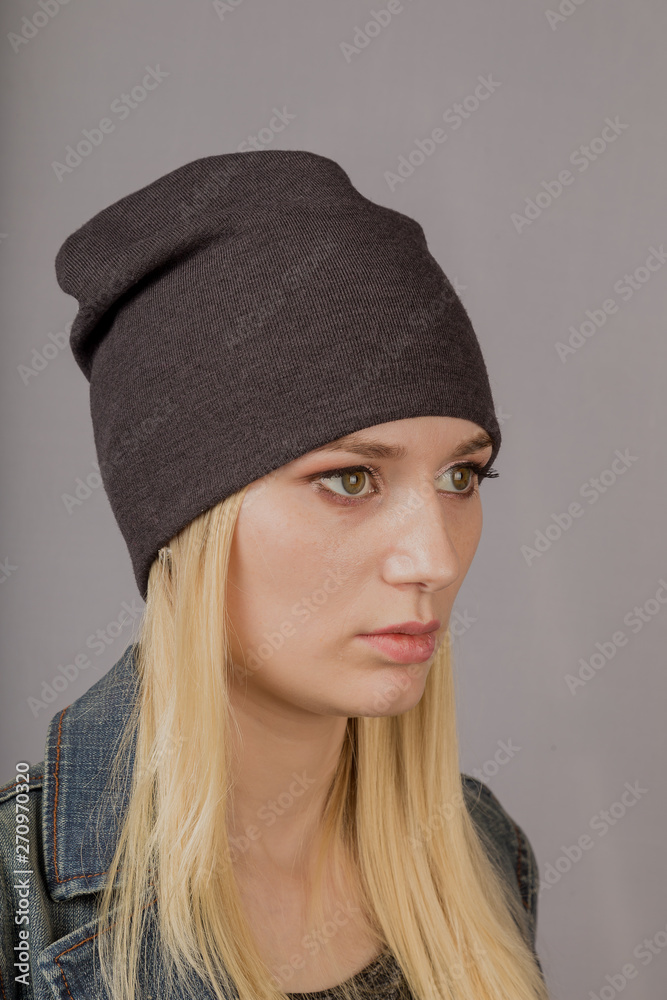 Portrait of a beautiful young girl in a stylish headdress with natural makeup on a gray background. Portrait of a beautiful young girl in a stylish headdress with natural makeup on a gray background.