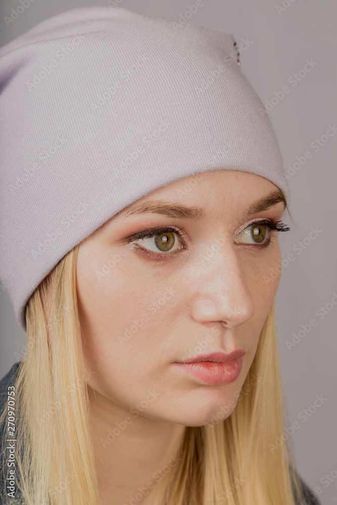 Portrait of a beautiful young girl in a stylish headdress with natural makeup on a gray background. Portrait of a beautiful young girl in a stylish headdress with natural makeup on a gray background.