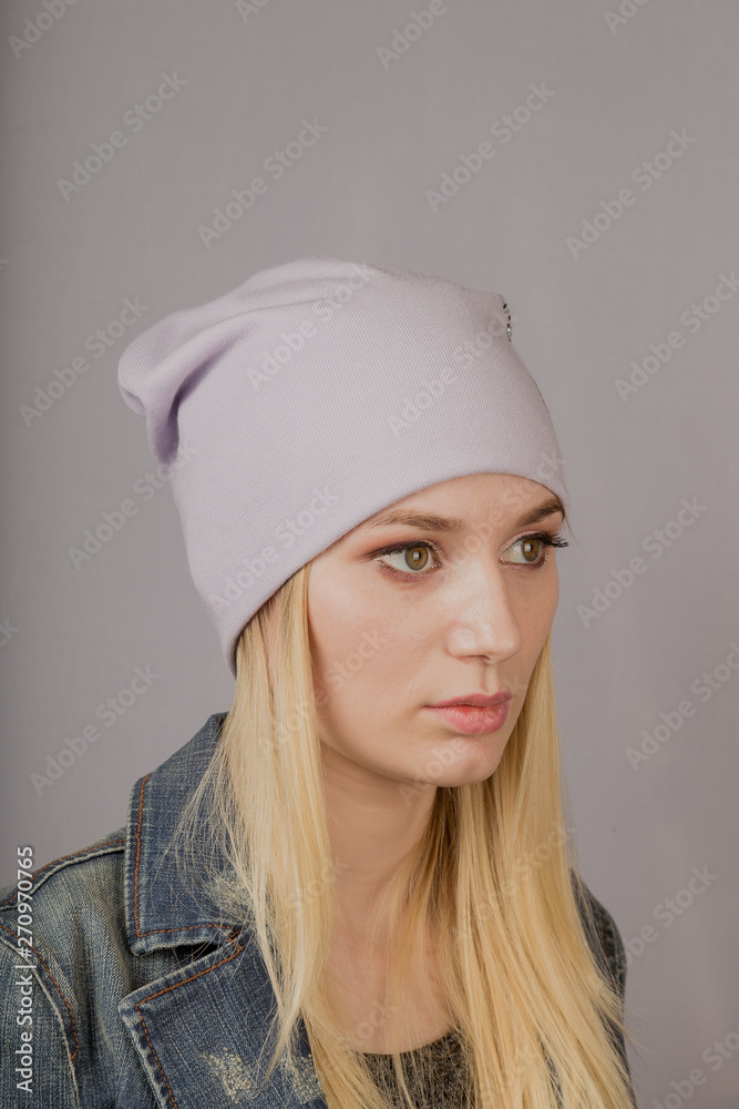 Portrait of a beautiful young girl in a stylish headdress with natural makeup on a gray background.