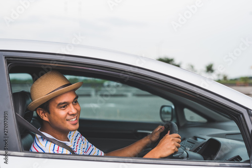 Young handsome asian man driving car with copy space. © Nopphon