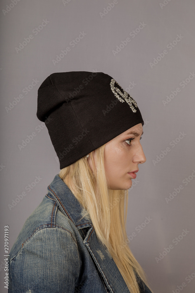 Portrait of a beautiful young girl in a stylish headdress with natural makeup on a gray background.