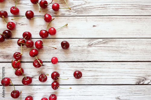 Red berries on a white wooden background. Top view, empty space