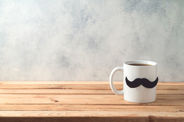 Happy Father's day concept with coffee mug and mustache over wooden background