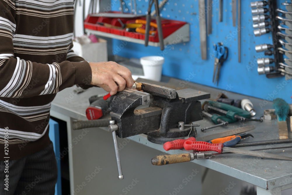 Handyman handles part in cast-iron vice in repair shop Handyman handles part in cast-iron vice in repair shop