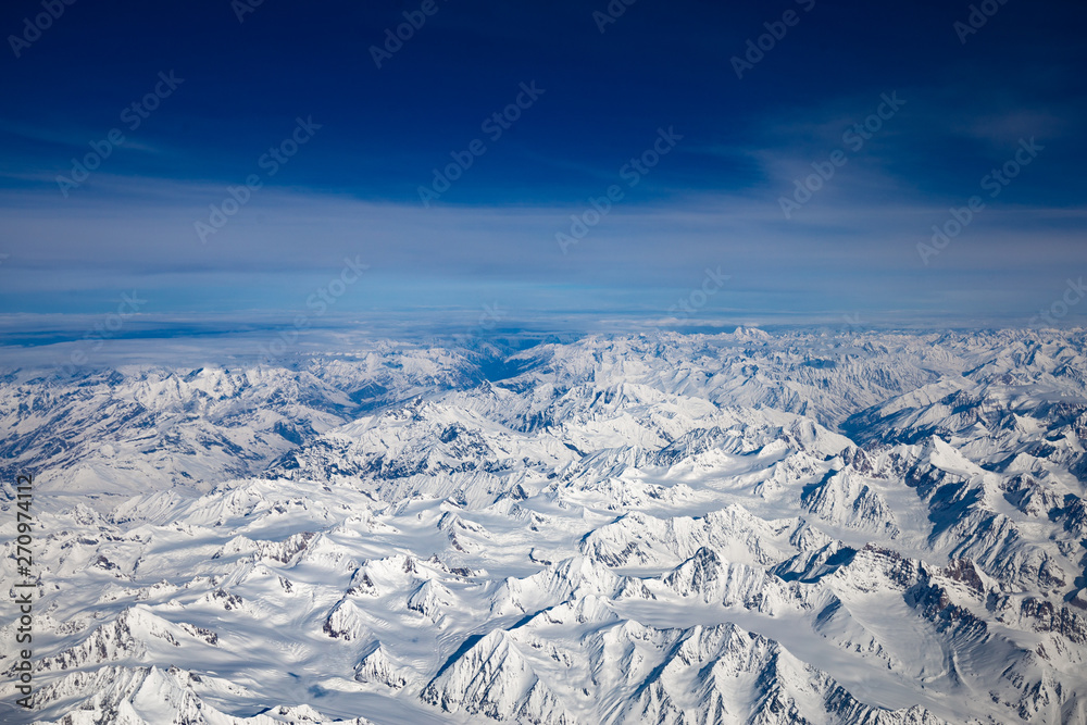 Fototapeta premium Aerial view from top of Himalayan mountains from the airplane window with Snow cover all of mountain range. Surface of white on peak hill over sky in Leh Ladakh, India.