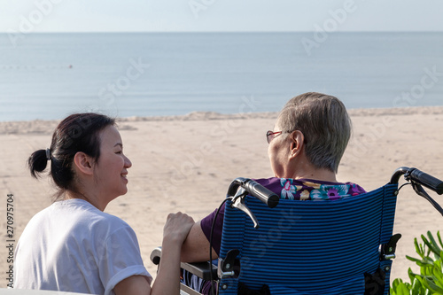 Obraz na płótnie Mother and daughter sit together in front of the beach looking at each other. w salonie
