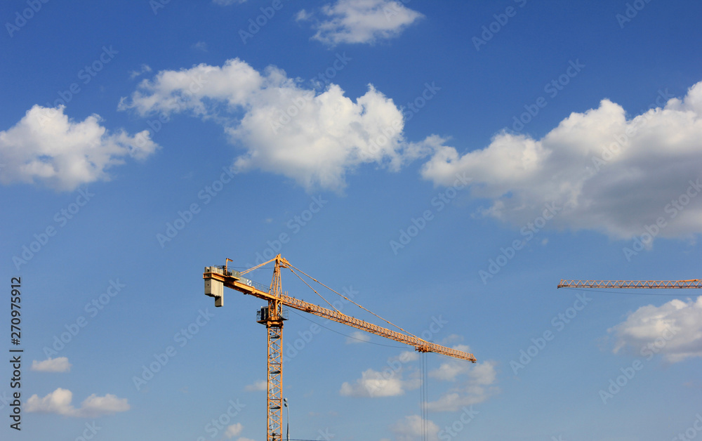 Construction site crane on blue sky background. Industrial work and engineering symbol Construction site crane on blue sky background. Industrial work and engineering symbol