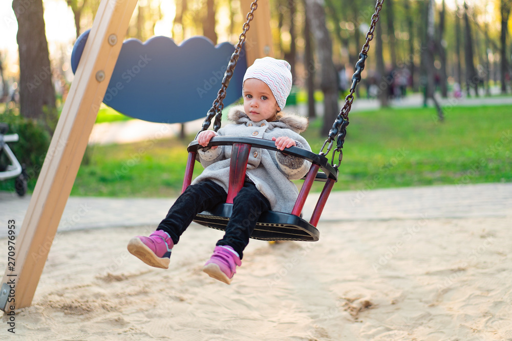 Happy child girl on swing in sunset fall. Little kid playing in the autumn on the nature park