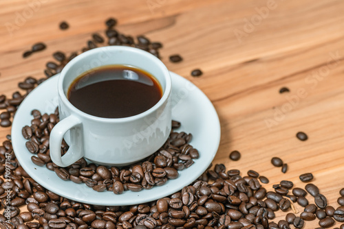 Cup of coffee and coffee beans on wooden background, Vintage tone