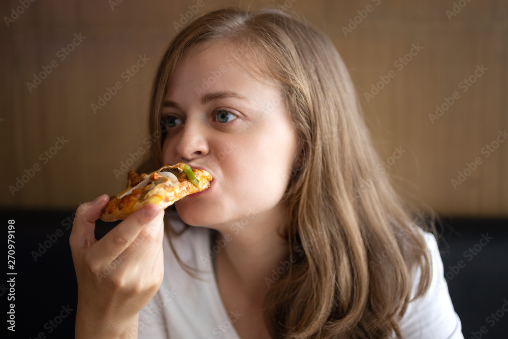 Young caucasian woman eating a slice of pizza Young caucasian woman eating a slice of pizza