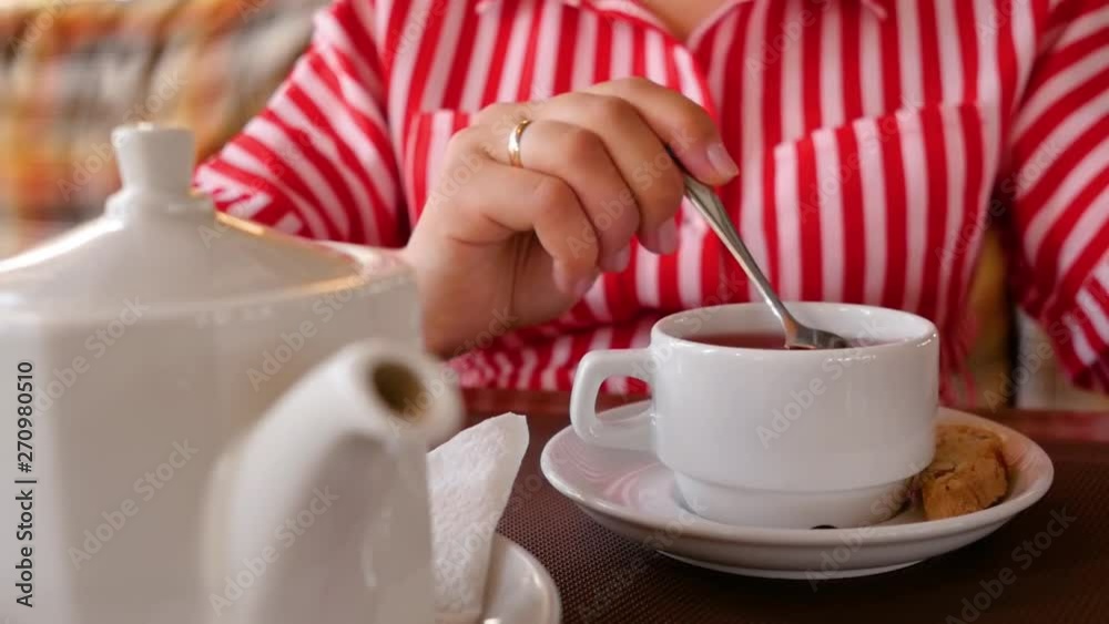 Woman pick up little spoon and start stirring sugar in cup of hot black tea. Close op shot. Woman pick up little spoon and start stirring sugar in cup of hot black tea. Close op shot.