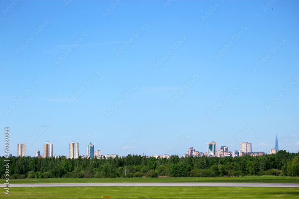 view of Saint Petersburg city silhouette from Pulkovo airport with runway and forest on the foreground