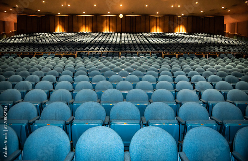 Auditorium with rows of blue seats with railing in back