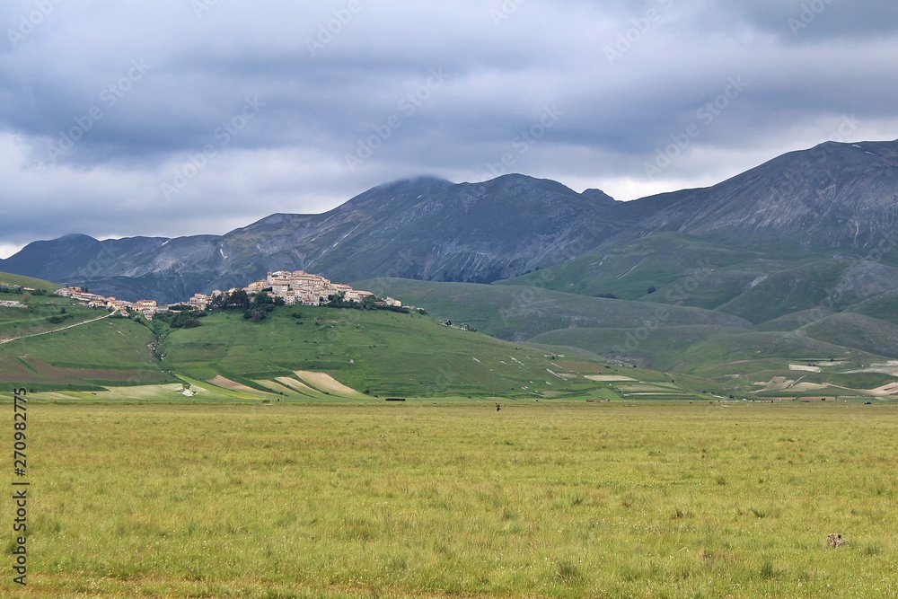 View of the plateau of Castelluccio di Norcia with the village on top of the hill (Umbria, Italy)