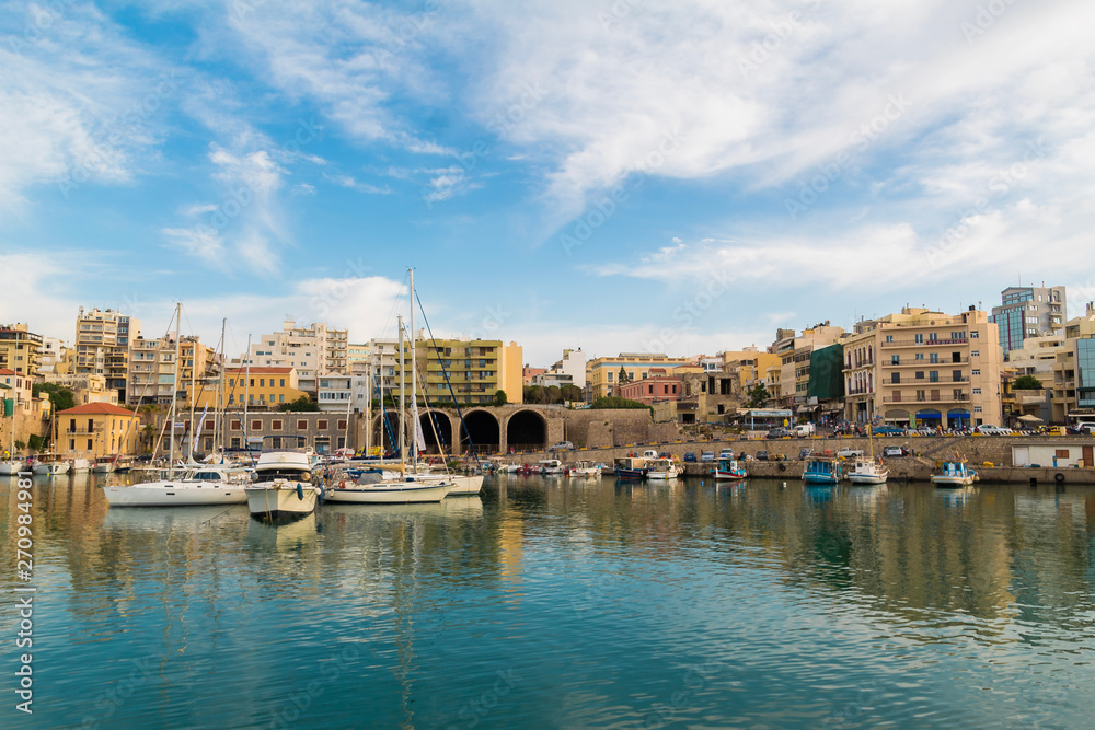 view of heraklion city old port and buildings clear sky calm blue water. calm day in summer