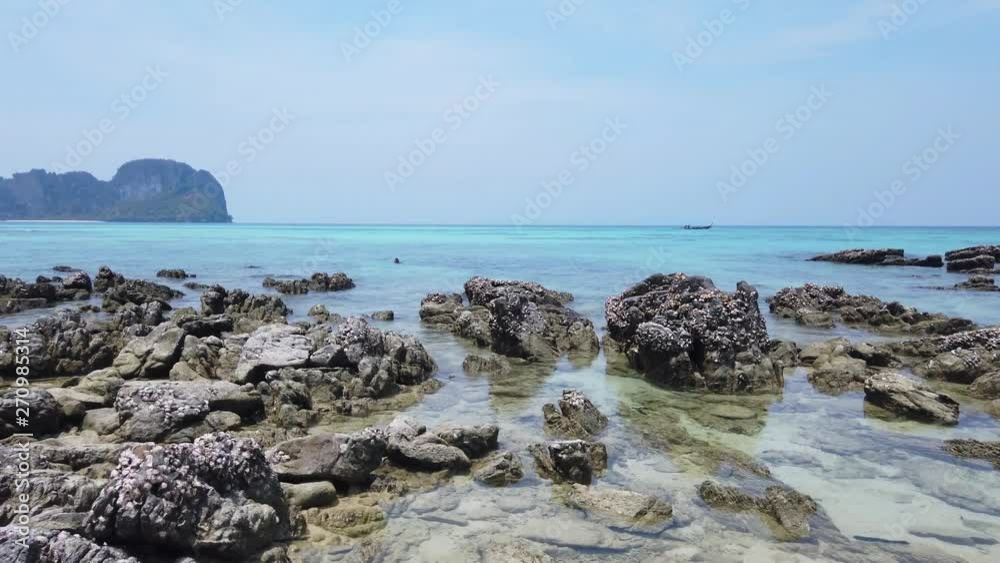 Tropical sea landscape with rocks at sand beach and rocky island at horizon. 4K clip Tropical sea landscape with rocks at sand beach and rocky island at horizon. 4K clip