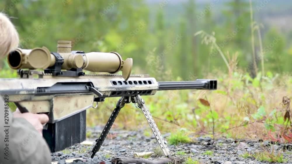 Sniper rifle shoots in slow motion on far away targer. Forest, summer. Sniper rifle shoots in slow motion on far away targer. Forest, summer.