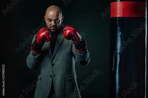 Businessman and sportsman in suit, man boxer in gloves with boxing punching bag. Trainings and © Mike Orlov